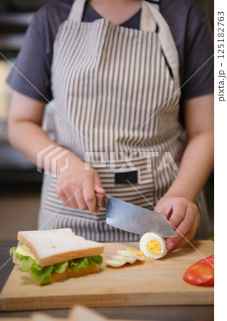Focused chef carefully a gourmet sandwich in a professional kitchen with fresh ingredients in view Focused chef carefully a gourmet sandwich in a professional kitchen with fresh ingredients in view 125182763