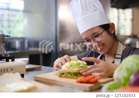 Focused chef carefully a gourmet sandwich in a professional kitchen with fresh ingredients in view Focused chef carefully a gourmet sandwich in a professional kitchen with fresh ingredients in view 125182833