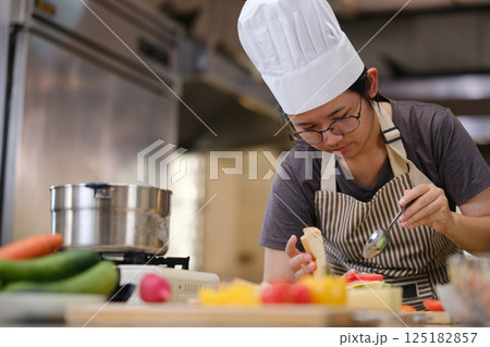 Focused chef carefully a gourmet sandwich in a professional kitchen with fresh ingredients in view 125182857