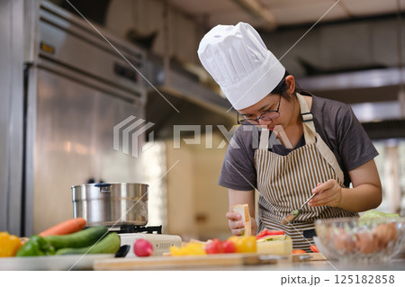 Focused chef carefully a gourmet sandwich in a professional kitchen with fresh ingredients in view 125182858
