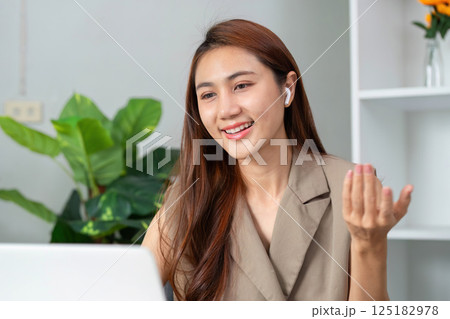 Video Conferencing and Communication. A young woman smiles during an online meeting, engaging with the audience. Video Conferencing and Communication. A young woman smiles during an online meeting, engaging with the audience. 125182978