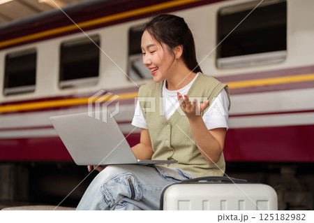Traveling and Digital Connection. A young woman engages in video calling while waiting for her train. 125182982
