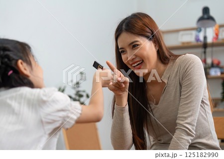 Playful Interaction and Learning Moments. A mother shares a laugh while playing dominoes with her daughter. Playful Interaction and Learning Moments. A mother shares a laugh while playing dominoes with her daughter. 125182990