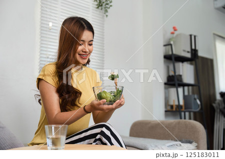 Healthy Eating and Morning Serenity. A woman cherishes her morning salad ritual, celebrating health and wellness. Healthy Eating and Morning Serenity. A woman cherishes her morning salad ritual, celebrating health and wellness. 125183011