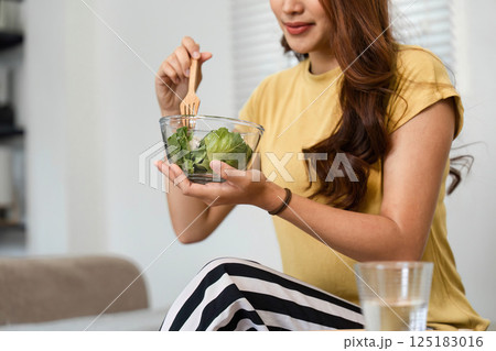 Morning Self-Care and Nutrition. A woman relishes a nourishing salad bowl while maintaining her healthy lifestyle. Morning Self-Care and Nutrition. A woman relishes a nourishing salad bowl while maintaining her healthy lifestyle. 125183016