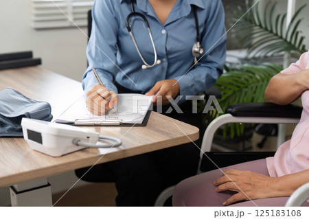 Consultation and Health Check. A healthcare professional documents patient information during a check-up. 125183108