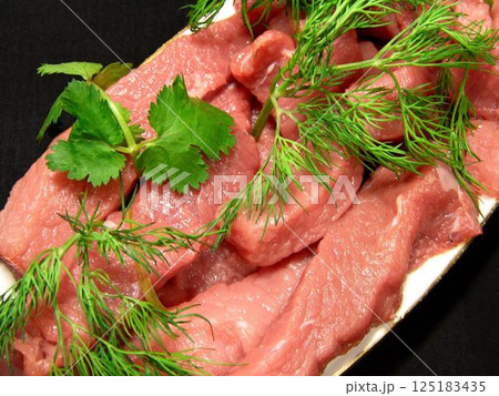 Raw uncooked meat with greens on a plate close view background Raw uncooked meat with greens on a plate close view background 125183435