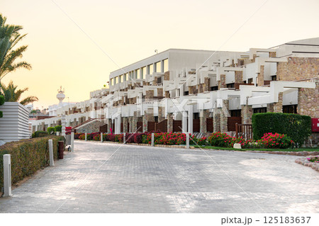 Beautiful resort complex with tranquil pathways surrounded by vibrant flowers at sunset 125183637