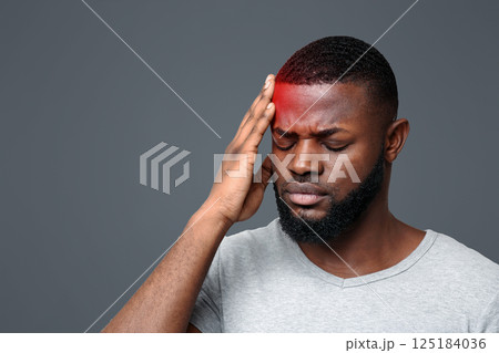 Young black man suffering from headache, touching highlighted forehead 125184036