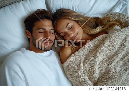 Close up of a young loving heterosexual couple sweet sleeping embracing each other. Captured in a sweet moment, the couple sleeps together, their loving embrace radiating serenity. 125184618