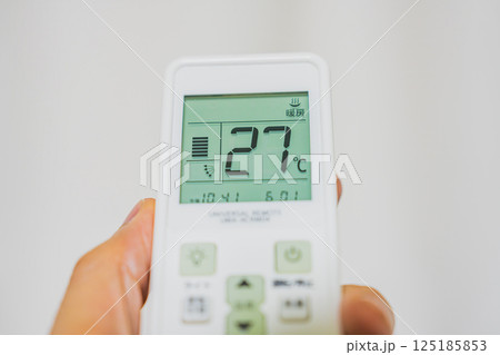 エアコンのリモコンを持つ手 125185853