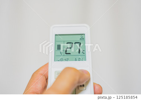 エアコンのリモコンを持つ手 125185854