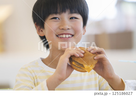 ハンバーガーを食べる笑顔の9歳の男の子 125186027