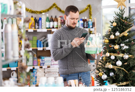 Middle-aged man scanning QR-code on gift basket in store during Christmas Middle-aged man scanning QR-code on gift basket in store during Christmas 125186352