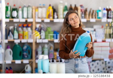 Young woman buyer chooses detergent in store 125186438
