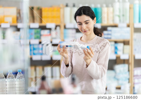 Young woman chooses ointment at pharmacy 125186680