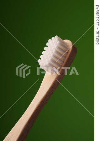 A wooden toothbrush on a green background. Oral health. Eco toothbrush. 125186843