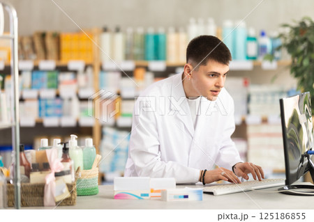Young man pharmacist uses computer at workplace 125186855