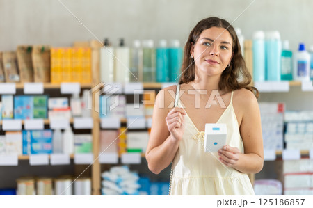 Girl buys emollient body cream at pharmacy Girl buys emollient body cream at pharmacy 125186857