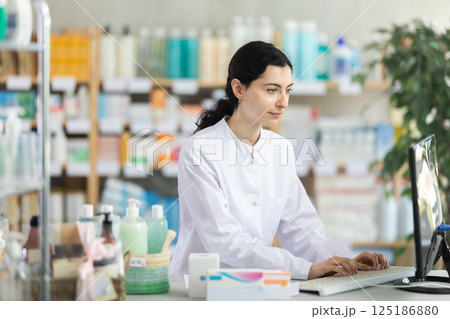 Female pharmacist working at computer in pharmacy 125186880