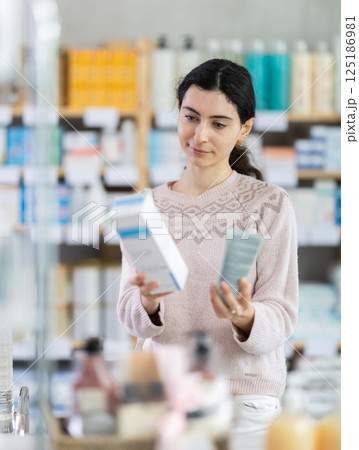 Young woman chooses cream at pharmacy Young woman chooses cream at pharmacy 125186981