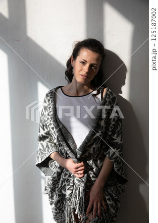 Beautiful brunette woman standing in the shadow of the light from the window 125187002