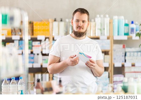 Man carefully selects pills in modern pharmacy Man carefully selects pills in modern pharmacy 125187031