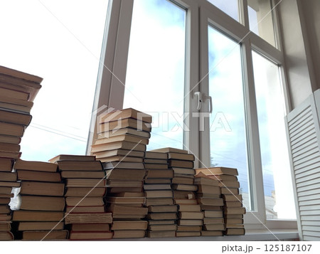 many stacks of books for learning at the window of the library 125187107