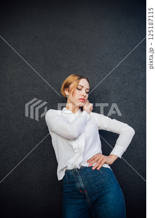 Portrait of a beautiful woman fashionably in jeans on a dark background Portrait of a beautiful woman fashionably in jeans on a dark background 125187115