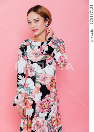 fashion blonde woman in summer dress with flowers on pink background smiling 125187121