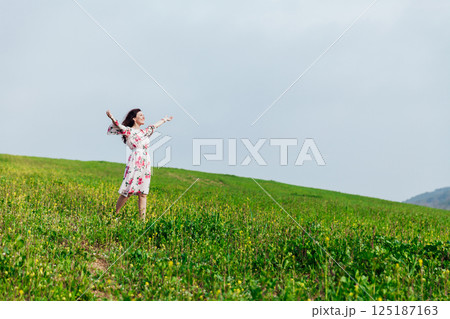 woman standing with her arms outstretched in a field of flowers in spring woman standing with her arms outstretched in a field of flowers in spring 125187163