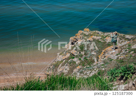 Female tourist taking photos of seascape from top of cliff 125187300