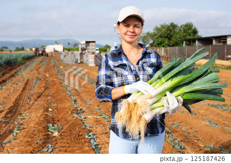Woman posing with leek crop on field Woman posing with leek crop on field 125187426