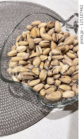 pistachios in a glass vase on a napkin on the table 125187462