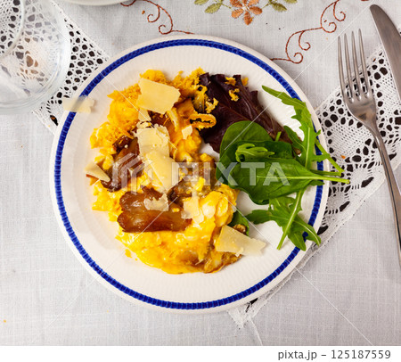Scrambled eggs with mushrooms and cheese served with greens 125187559