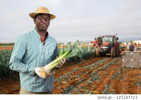 African american man with a leek in hand in field 125187721