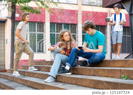 Teenage boy and girl sitting on steps near school Teenage boy and girl sitting on steps near school 125187724