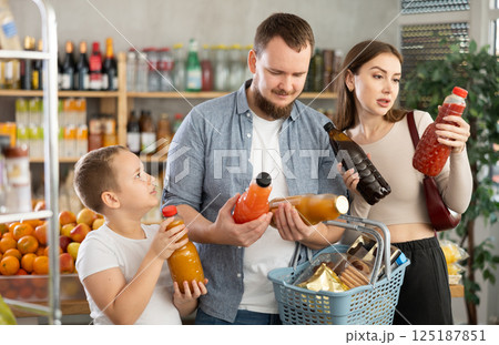 Couple of man and woman with boy choosing juices in grocery 125187851
