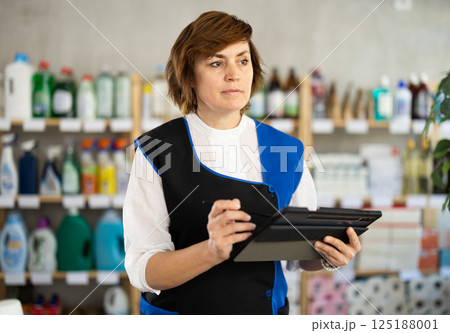 Adult woman seller conducting inventory with tablet 125188001