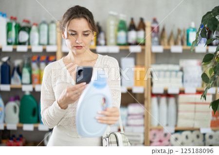 Woman client scans QR code on package and downloads promo code to purchase liquid powder Woman client scans QR code on package and downloads promo code to purchase liquid powder 125188096