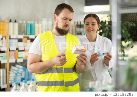 Laboring man builder buys pills at pharmacy, consulting with girl pharmacist Laboring man builder buys pills at pharmacy, consulting with girl pharmacist 125188298
