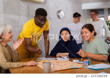 Cheerful african american man playing board game with friends Cheerful african american man playing board game with friends 125188299