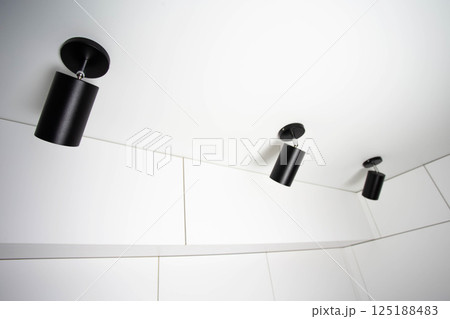 Modern black LED spotlights on white ceiling. Copy space for text 125188483