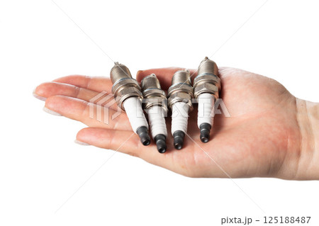 Car spark plugs in a girl's hand on a white background, isolate. Close-up 125188487