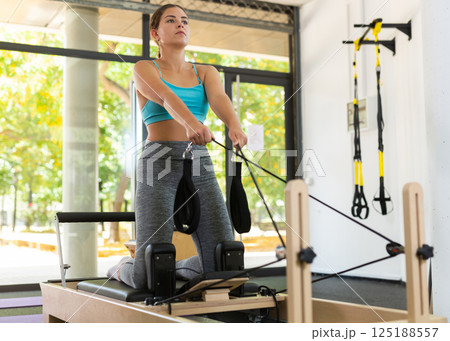 Young woman doing exercises on pilates reformer 125188557