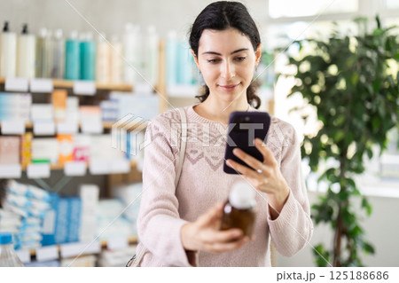 Woman scans the barcode of medicated syrup for cough 125188686