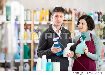 Female consultant helps man buyer choose home chemical spray Female consultant helps man buyer choose home chemical spray 125188791