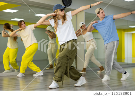 Teenage girl in sunglasses and cap training breakdance Toprock moves in dance hall Teenage girl in sunglasses and cap training breakdance Toprock moves in dance hall 125188901