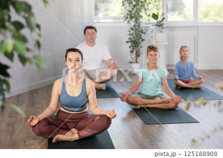 Family with two children doing yoga in studio 125188908