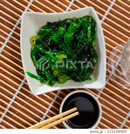 Chuka seaweed with sesame seeds in white bowl and wooden sticks Chuka seaweed with sesame seeds in white bowl and wooden sticks 125188909